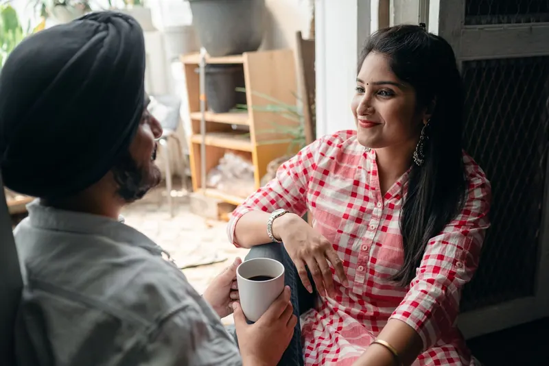 Couple sitting together at home holding mugs and talking calmly