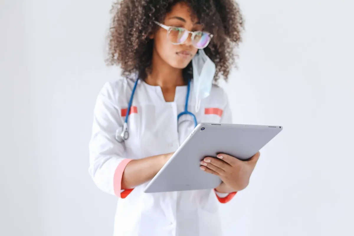Doctor in a white coat with a stethoscope reviewing information on a tablet