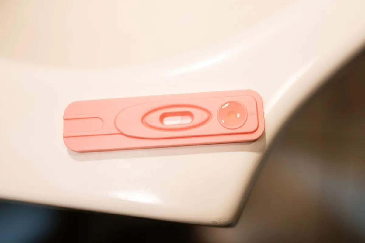 Pink test cassette resting on the edge of a white bathroom sink