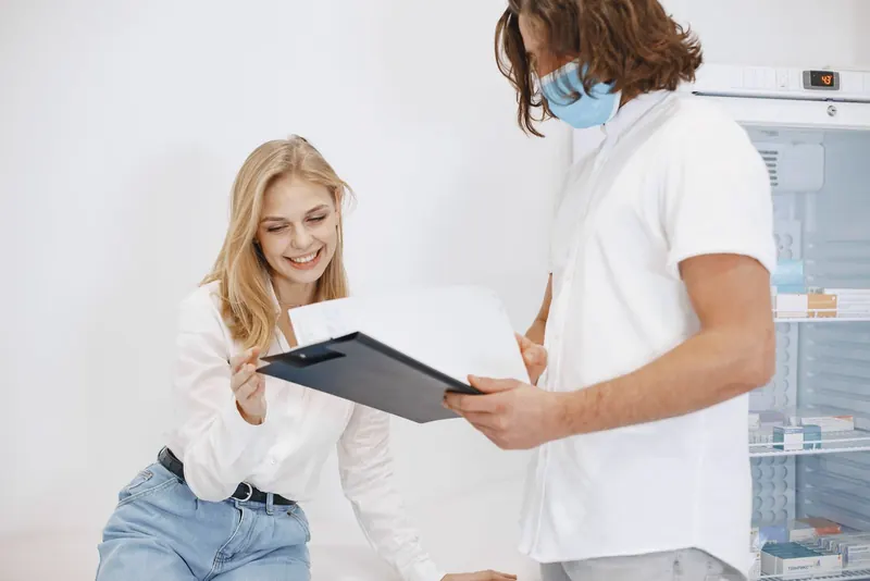 Smiling patient reviewing results on a clipboard with a clinician in a bright exam room