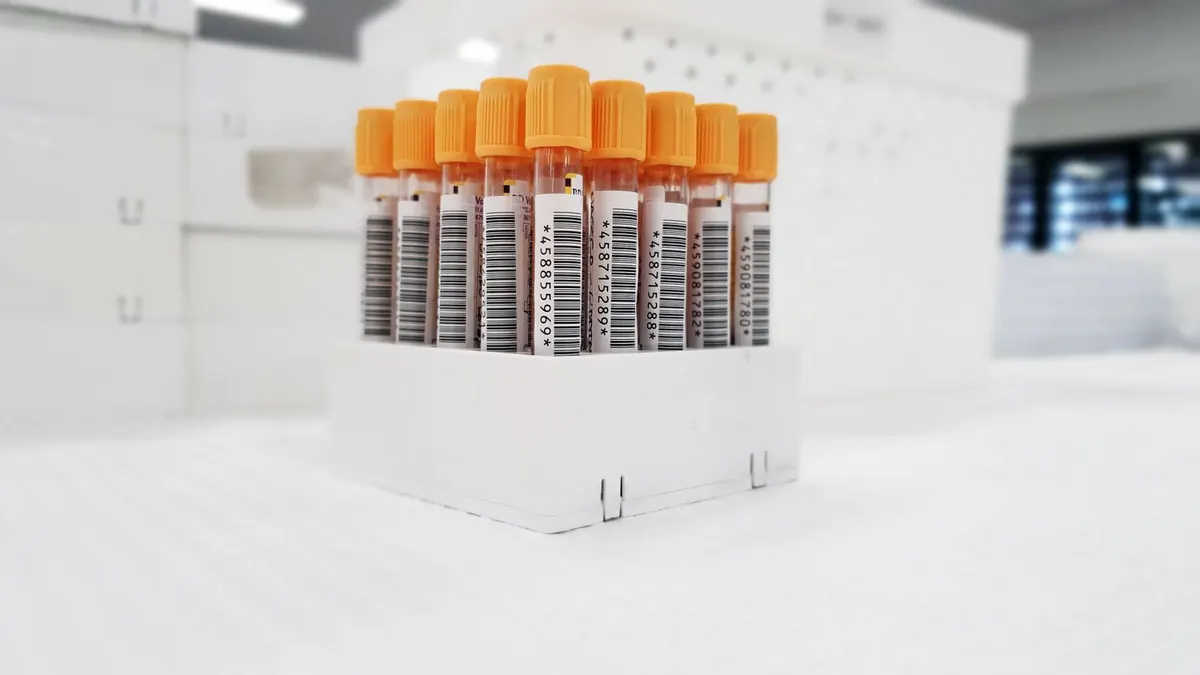 Rack of capped blood sample tubes on a white lab bench
