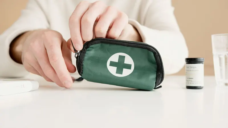 Hands unzipping a green kit pouch on a white table beside a test strip vial and a glass of water