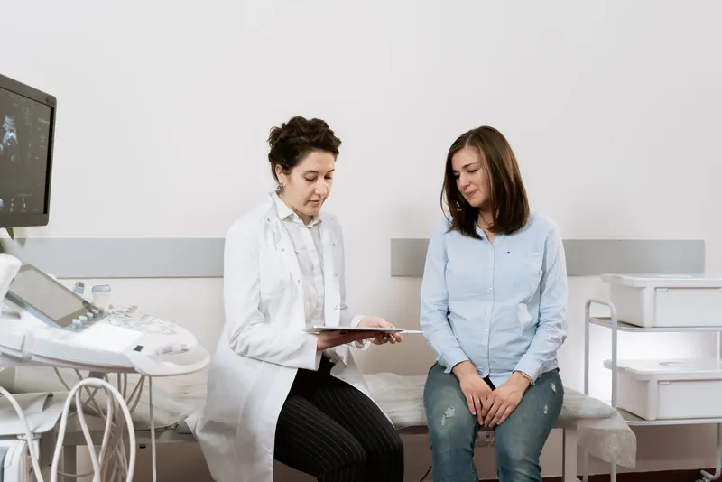 Pregnant patient sitting with her doctor during a prenatal consultation in a clinic room